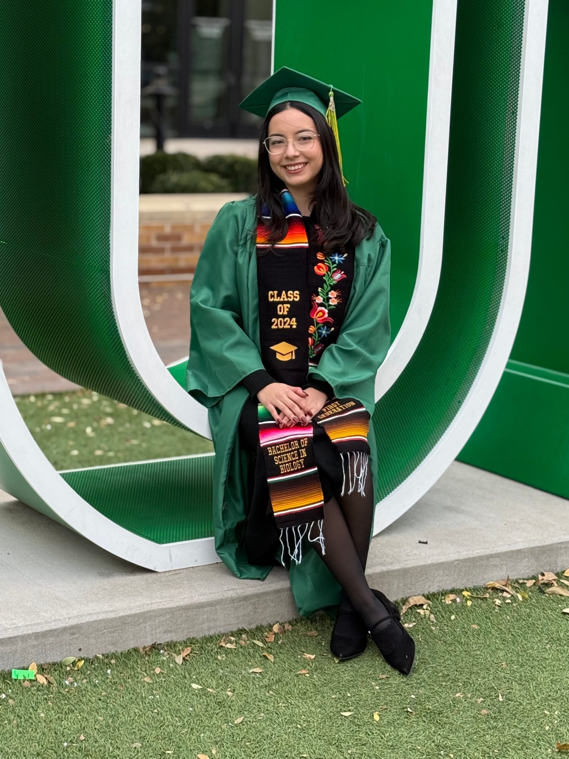 Woman posing for picture wearing graduation cap and gown